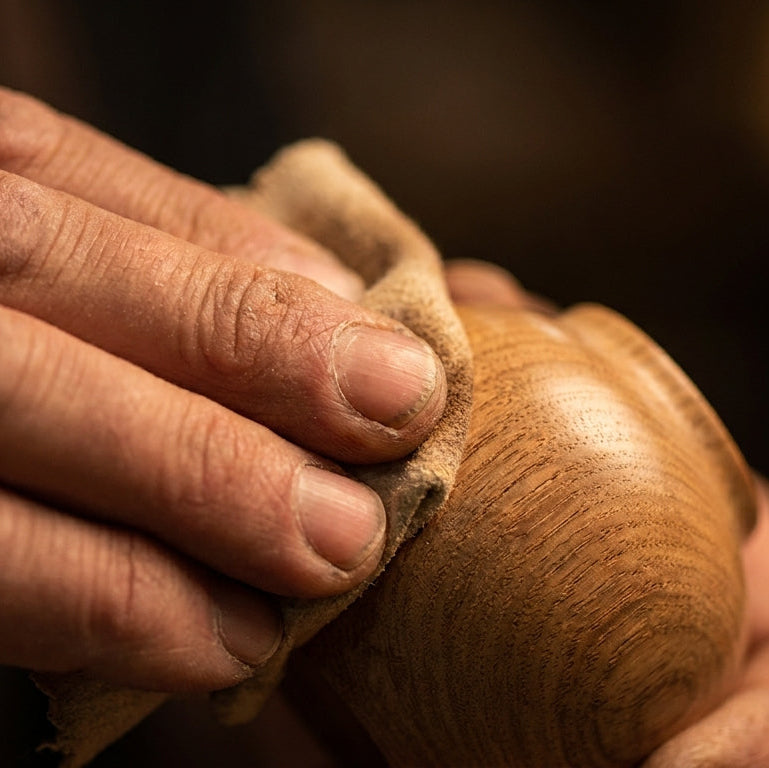 Close-up of a hand holding a wooden object with a blurred background